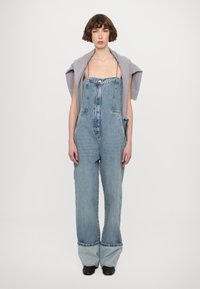 Denim kombinezoni v svetlo modri barvi s prilegajočim zgornjim delom, širokimi hlačnicami in zavihanimi robovi. Imajo sprednje gumbne zap closures in sprednje žepe.