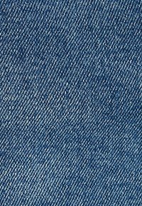 Denimtyg i mörkblått, med ett klassiskt twill-vävmönster, synlig textur och en lätt lyster från fibrerna.