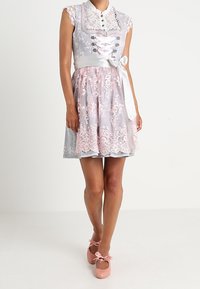 Abito con pizzo grigio chiaro e rosa, dal taglio aderente, colletto, apertura con lacci e cintura in raso. Abbinato a scarpe rosa.