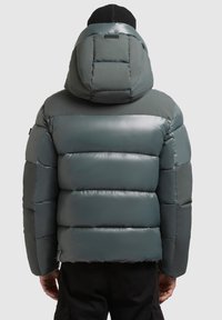 Kurtka puchowa w ciemnozielonym kolorze z błyszczącym wykończeniem, wyposażona w kaptur, pikowany wzór i elastyczne mankiety. Minimalistyczne logo na plecach.