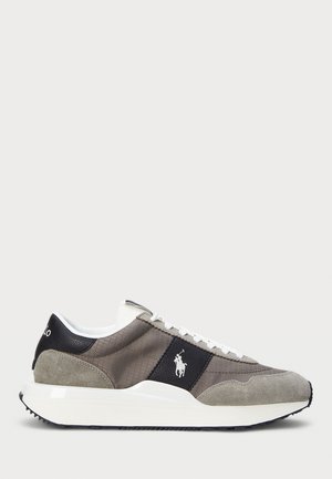 Grå sued og tekstil sneakers med hvite snøringer, sorte detaljer og en hvit såle. Har en logo på siden. Teksturert overdel.