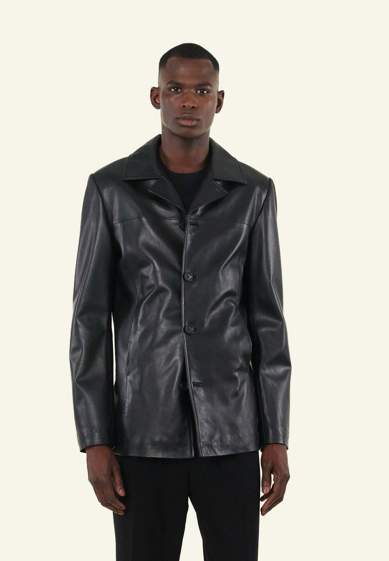 Zwarte leren jas met een omgeslagen kraag, sluiting met knopen aan de voorkant en een gladde textuur. Beschikt over lange mouwen en een getailleerde pasvorm.