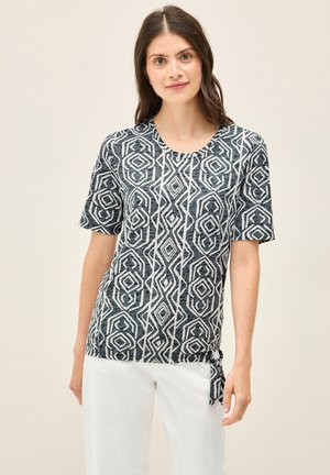 Korte mouw top in donkerblauw met wit geometrisch patroon; ronde halslijn; geknoopt detail aan de zijkant; lichtgewicht, gestructureerde stof.