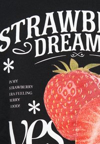 Tissu noir avec un grand motif de fraise rouge et le texte "STRawberry DREAMS" en blanc, accompagné de textes et d'éléments de design plus petits.