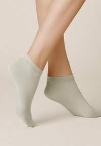 Helle grüne Knöchelsocken aus weichem, dehnbarem Material, mit einem gerippten Bündchen und einer glatten Textur, die eine enge Passform bieten.