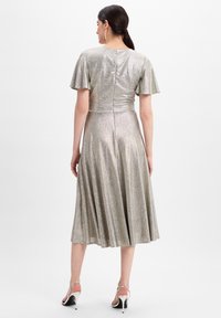 Metallisch silbernes Kleid mit flatternden Ärmeln, figurbetontem Oberteil und ausgestelltem Rock. Glatte Textur, knielang und mit Reißverschluss auf der Rückseite.