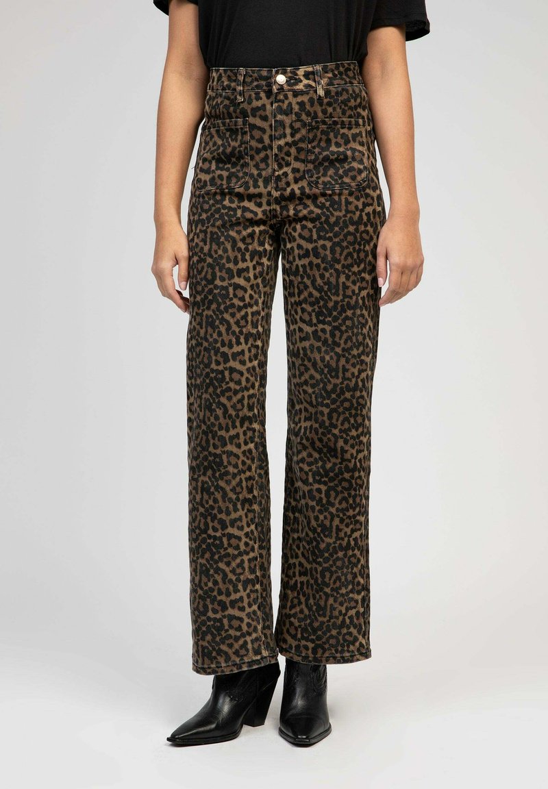 Pantalons larges à imprimé léopard en tissu marron et noir, dotés d'une taille haute et de deux poches avant, associés à des bottes noires à talons pointus.