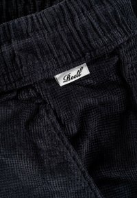 Black corduroy fabric with a ribbed texture; features an elastic waistband and a label with the brand name "Lkeell."