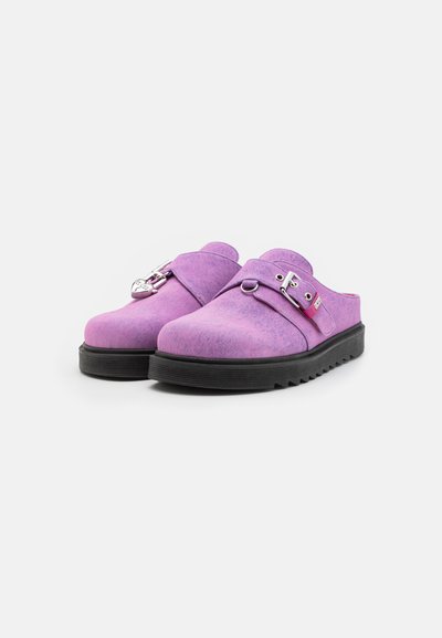 Lilla slip-on sko med et tekstureret stofoverdel, rund tå, justerbar rem med sølvspænde og sort gummisål.