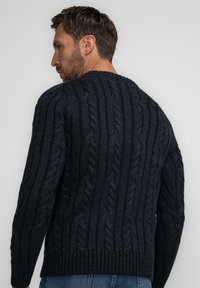 Marineblauer gestrickter Pullover mit einem Zopfstrickmuster, ausgestattet mit einem gerippten Saum und Bündchen. Der Stoff hat eine strukturierte, voluminöse Oberfläche.