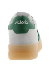Baskets blanches avec des accents verts et un talon en daim. Présente une semelle en caoutchouc translucide et le logo "victoria" sur l'étiquette du talon.