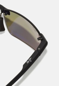 Gafas de sol negras con un acabado brillante, que cuentan con lentes oscuros con degradado. Incluyen herrajes plateados y branding en la patilla.