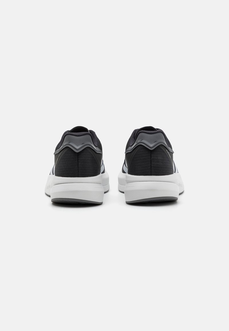 Zapatillas negras y grises con parte superior de tejido suave, un soporte trasero destacado y una entresuela blanca con un patrón texturizado.