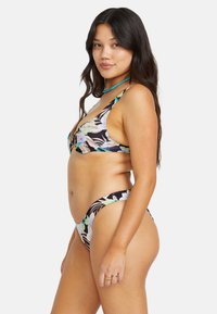 Bikini-set med blommigt mönster på svart bakgrund, där toppen har tunna axelband och en triangulär form, medan botten har en högskuren design.