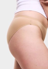 Mutande hipster beige realizzate in tessuto morbido, con un design senza cuciture e una cintura elastica morbida per il massimo comfort.