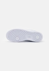 White sneaker sole with textured rubber, featuring circular patterns and a Nike logo. Smooth edges and a flat profile.