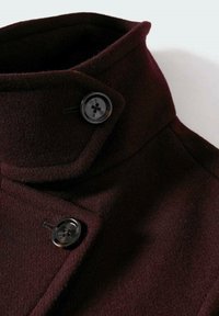 Manteau en laine bordeaux à double boutonnage, avec un col montant et deux boutons noirs pour la fermeture. Texture douce et lignes épurées.