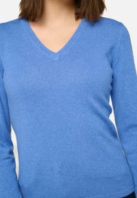 Pull en V bleu clair en tissu doux et côtelé avec des manches longues. Présente une texture lisse et une coupe ajustée.