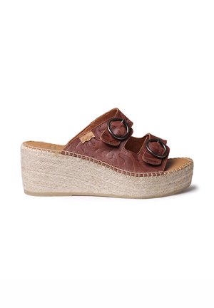 Bruine wig-slippersandalen met twee decoratieve ronde hardwareaccenten, bovenwerk van textuurleer en een geweven jute-beklede platformbasis.