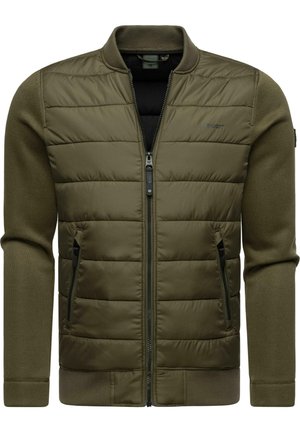Chaqueta acolchada color verde oliva con mangas y cuello de punto acanalado, cierre con cremallera frontal y dos bolsillos laterales. Presenta el logo en la parte superior izquierda del pecho.