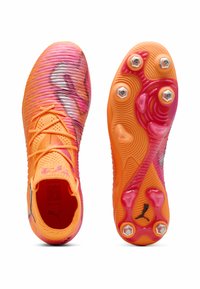 Scarpini da calcio arancioni brillanti con tomaia testurizzata rosa e argento, caratterizzati da un design con lacci e una suola arancione rigata con tacchetti.