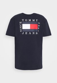 Navy blue cotton t-shirt with short sleeves. Back features a rectangular logo in red, white, and navy, and "TOMMY JEANS SINCE 1985" text.