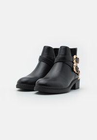 Botines de cuero negro hasta el tobillo con punta redonda, acentos de doble hebilla y un tacón bajo cuadrado. Textura suave y detalles de costura mínimos.