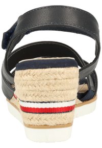 Marineblaue Leder-Espadrille-Sandale mit einer geflochtenen Jutewedge-Ferse, die einen weißen und roten gestreiften Akzent und einen verstellbaren Riemen an der Rückseite aufweist.