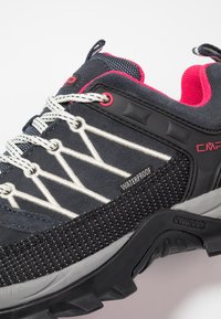 Black waterproof hiking shoe featuring a textured upper, white zigzag stitching, rubber outsole, and red accents on the collar and eyelets.