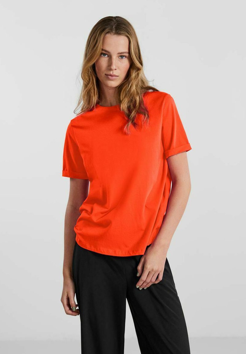 Orange kortærmet t-shirt i et blødt, glat stof. Klassisk crew neck-design med opkrøllede ærmer og en afslappet pasform.