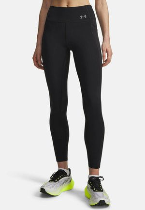 Schwarze Leggings aus elastischem Material mit hohem Bund und reflektierendem Logo. Kombiniert mit grauen und neon-grünen Laufschuhen.