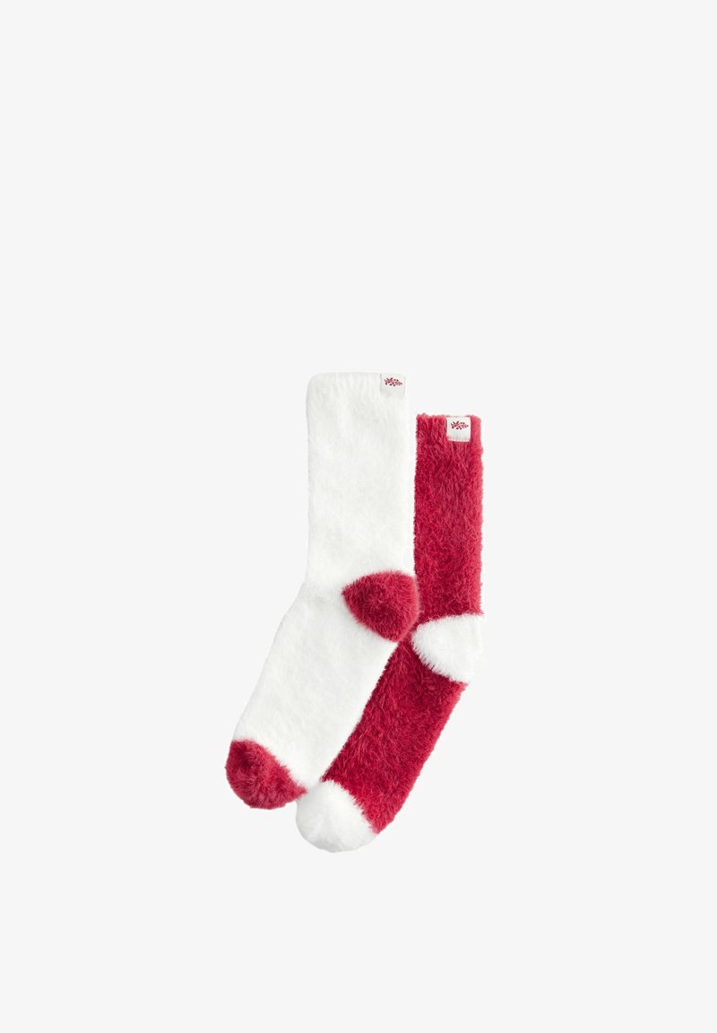 Minkšti, pūkuoti batai balta ir raudona spalvomis su kontrastingomis pirštų ir kulno akcentais. Viršuje esantys etiketės turi mažą logotipą.