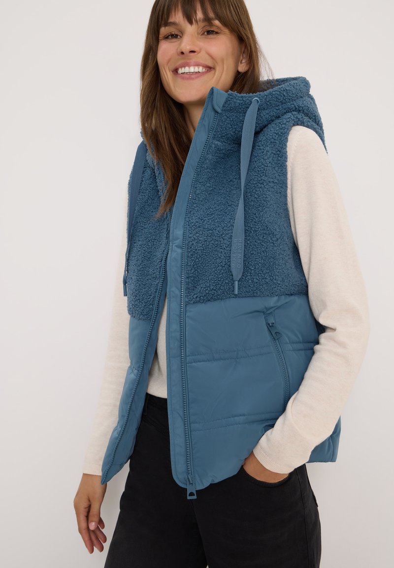 Blaues ärmelloses Vest mit einer flauschigen, strukturierten Oberseite, einem glatten unteren Abschnitt und einer Kapuze. Verfügt über einen Reißverschluss und Taschen.