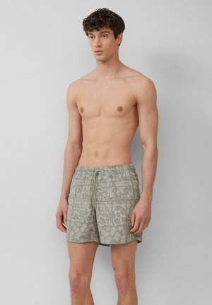 Shorts de bain verts à motifs avec une taille élastique à cordon, ornés de motifs floraux. Fabriqués en tissu léger, conçus pour le confort et la mobilité.