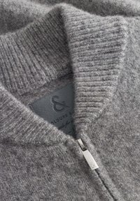 Grau gestrickter Wollmischpullover mit einem gerippten Kragen, glatter Textur und einem silbernen Reißverschluss mit einem kleinen Logodetail.