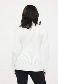Weißer gerippter Pullover mit vertikalen Streifen und taillierter Silhouette, langen Ärmeln und hochgeschlossenem Kragen. Strukturierter Strickdesign.