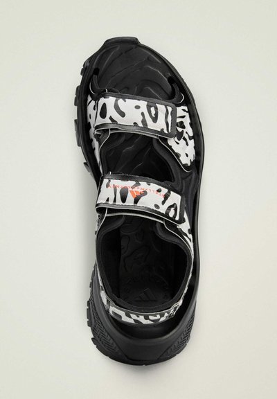 Zwart-witte sandalen met leopardenprint banden, voorzien van verstelbare klittenbandsluitingen en een gestructureerde zwarte rubberen zool.