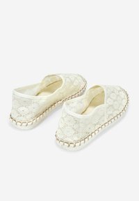 Espadrilles blancas de encaje con aperturas elásticas, textura trenzada y costuras beige contrastantes a lo largo de la suela. Diseño ligero y casual.
