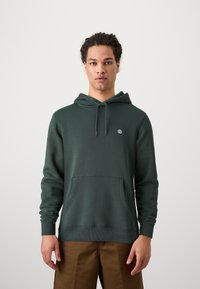 Dark green hoodie made of soft fabric, featuring a kangaroo pocket, ribbed cuffs, and a small logo on the chest.