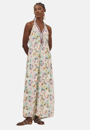 Vestido maxi con cuello halter, patrón floral multicolor sobre un fondo claro, con un detalle en forma de ojal y sandalias planas.