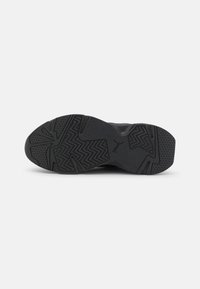 Suola di scarpa sportiva nera con superficie testurizzata e un motivo a spina di pesce, con un logo centrale. Materiale in gomma resistente.