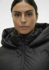 Černá vyp padded bunda s vysokým límcem a viditelným zipem, vyrobená z hladkého, lesklého materiálu, s kapucí a těsným střihem.
