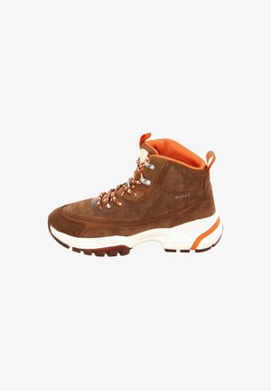 Brown suede hiking boot with orange accents, padded collar, and a thick white sole. Features metal eyelets and contrasting laces.