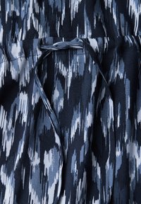 Texturiertem Stoff in verschiedenen Schattierungen von Marineblau und Hellblau mit einem abstrakten Muster. Verfügt über eine gebundene Taillendetail für eine verstellbare Passform.