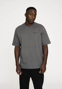 Grå kortærmet t-shirt lavet af blødt stof, med rund halsudskæring og et lille sort logo på venstre bryst. Klassisk pasform.