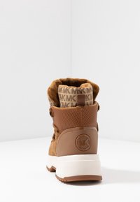 Bottines en daim marron avec un col rembourré, des détails en mesh et un accent logo. Caractéristiques d'une semelle blanche épaisse et d'un design à lacets.