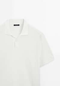 Polo blanc à manches courtes avec col classique et patte de boutonnage à deux boutons, posé à plat sur fond blanc.