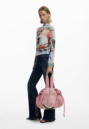 Rosa Stoffhandtasche mit doppelten Griffen, gerafftem Design und geflochtenen Akzenten, kombiniert mit einem mehrfarbigen bedruckten Oberteil und dunklen Schlagjeans.