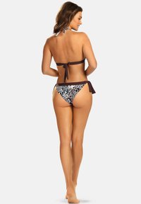 Dwuczęściowy bikini z górą na halter w jednolitym brązowym kolorze oraz z dołami w niskim stanie z wzorem i wiązaniami. Materiał ma gładką teksturę.
