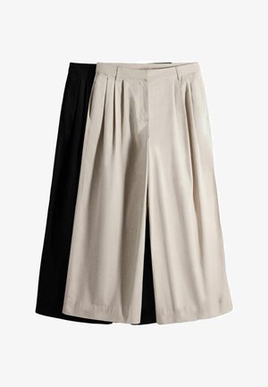 Kaksi paria leveälahkeisia housuja, yksi beige edessä ja yksi musta takana, molemmissa laskokset ja korkeat vyötärönauhat.